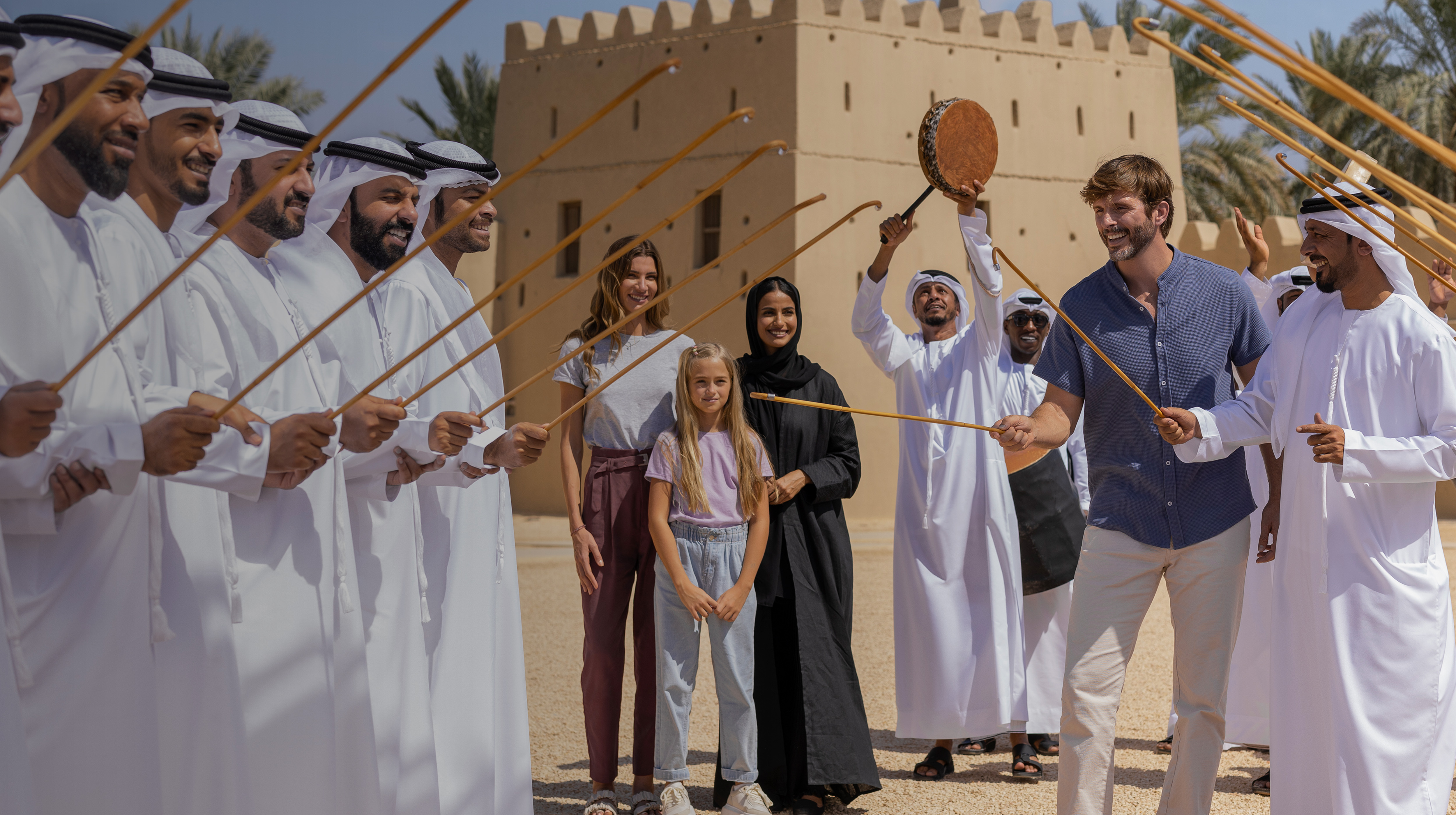 Visitors experiencing a traditional Emirati Ayala dance performance in Al Ain with joyful local participation.
