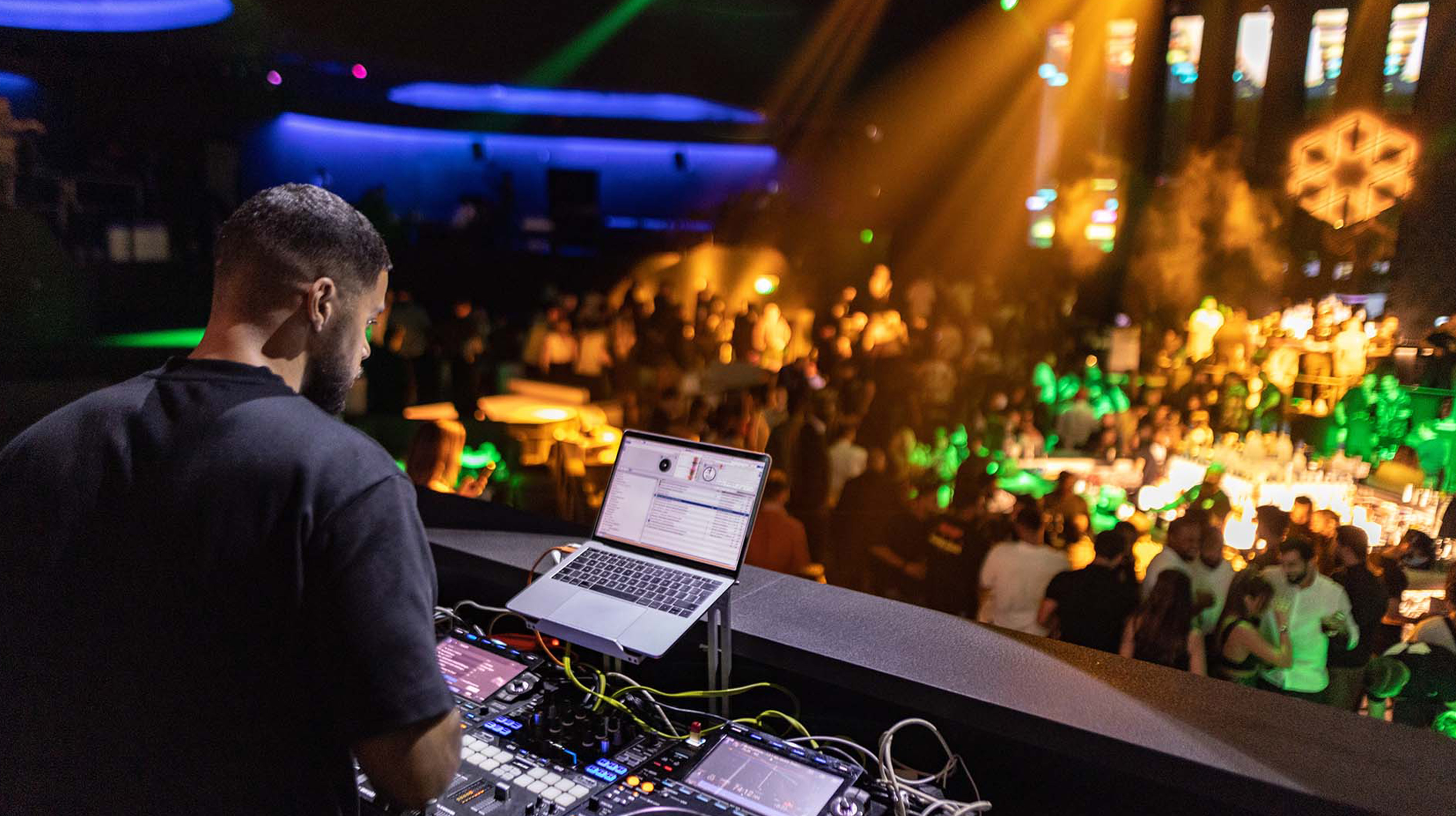 DJ performing live at a vibrant nightclub in Abu Dhabi with a packed crowd and colorful lights