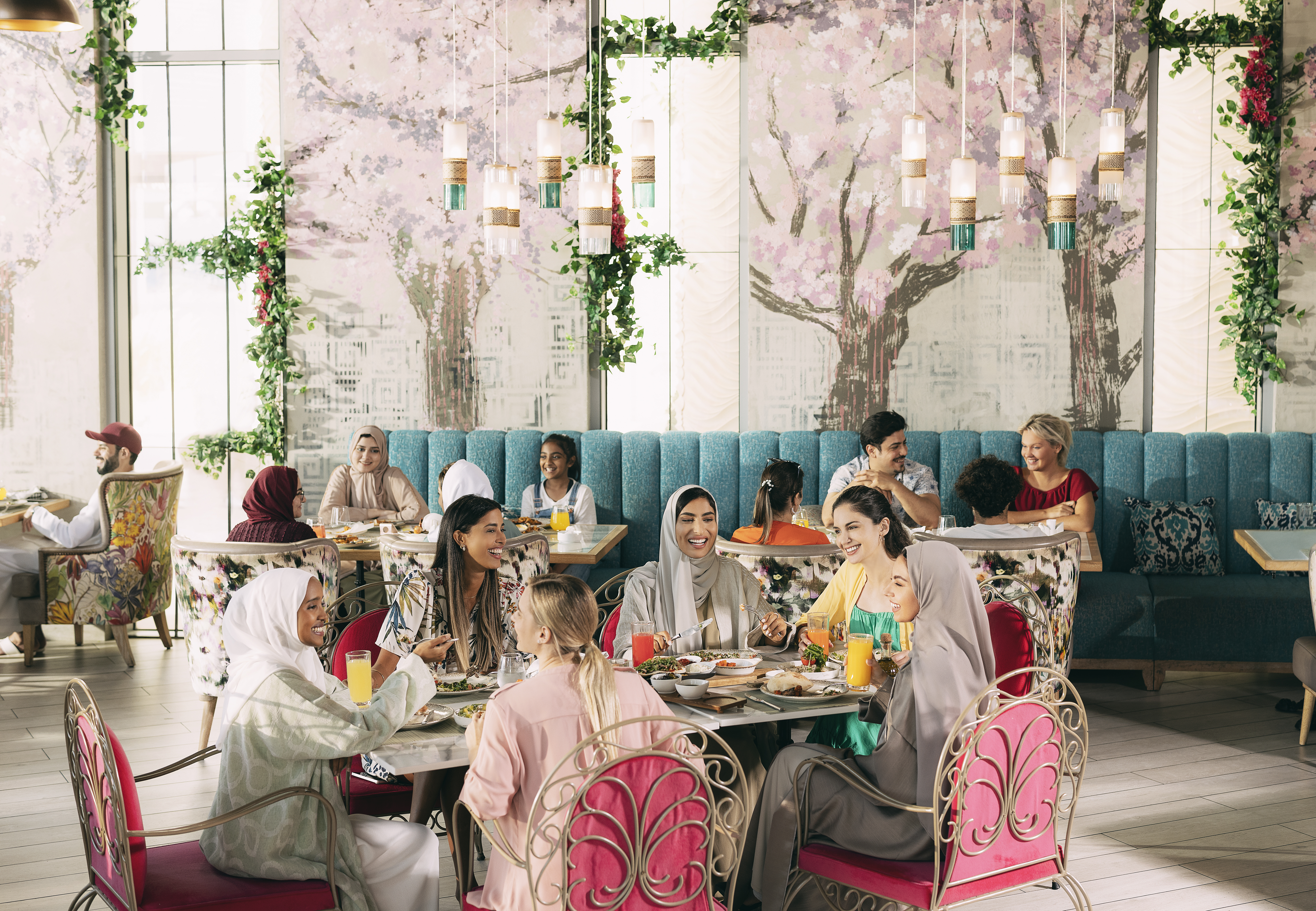 Group of friends enjoying a vibrant brunch in a floral-themed Abu Dhabi café with natural lighting