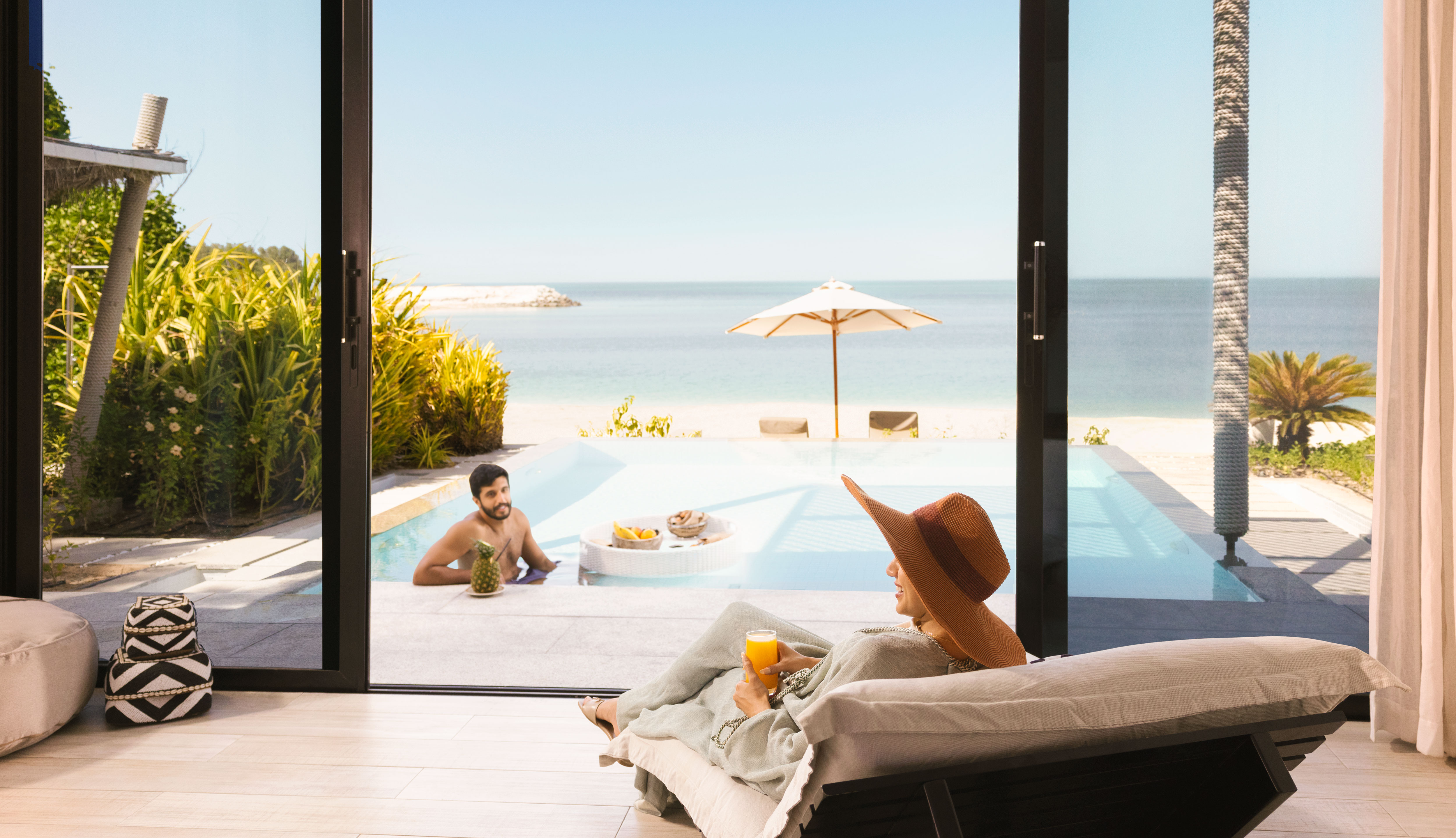 Couple enjoying a beachside private pool with floating breakfast and ocean view.
