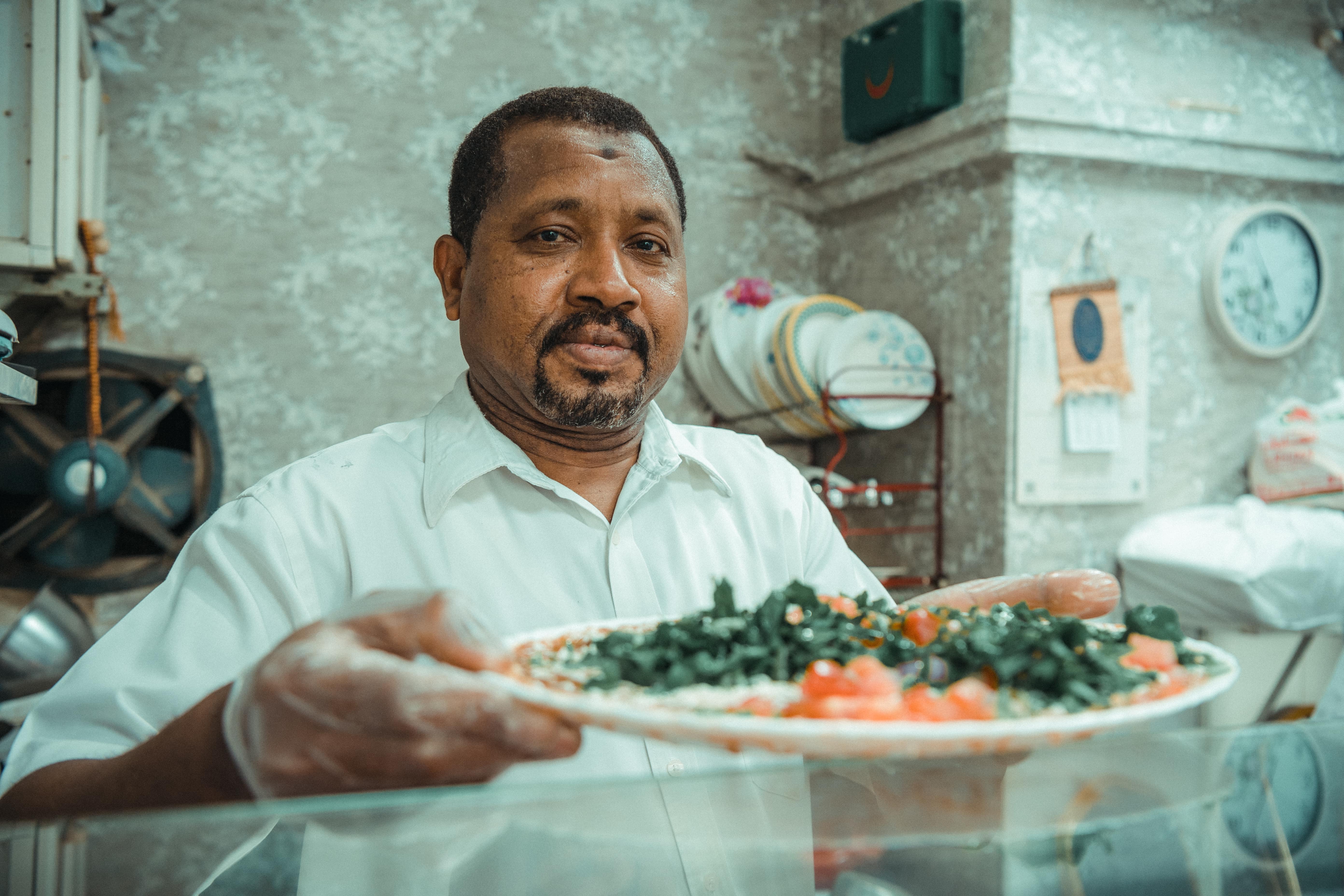 Local chef proudly presenting a freshly prepared traditional dish at an authentic eatery in Abu Dhabi.