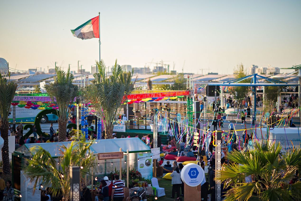 Vibrant outdoor community festival in Abu Dhabi with local stalls, decorations, and UAE flag flying high.