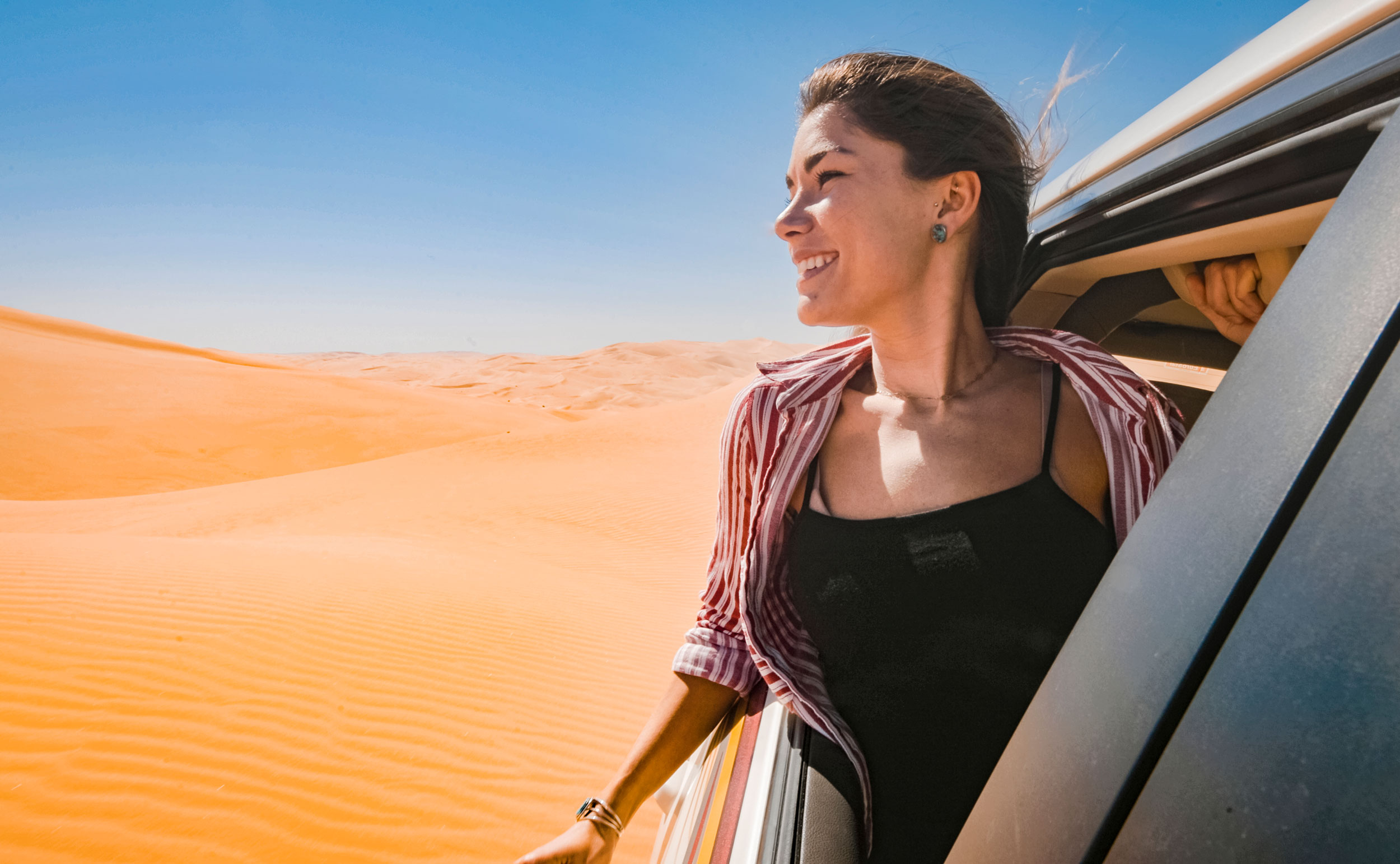 Woman enjoying desert views from a safari vehicle during a thrilling dune adventure in Abu Dhabi’s sand dunes.