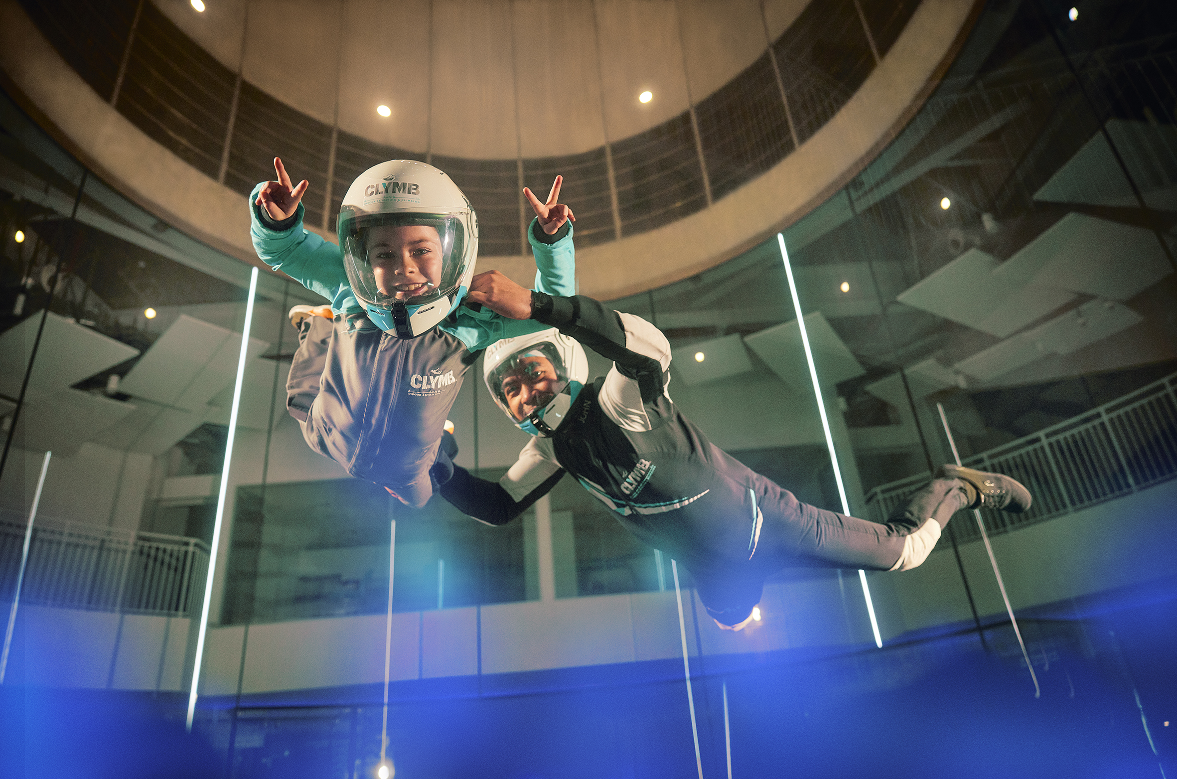 Bambino e istruttore in tuta e casco sperimentano lo skydiving a Clymb di Abu Dhabi